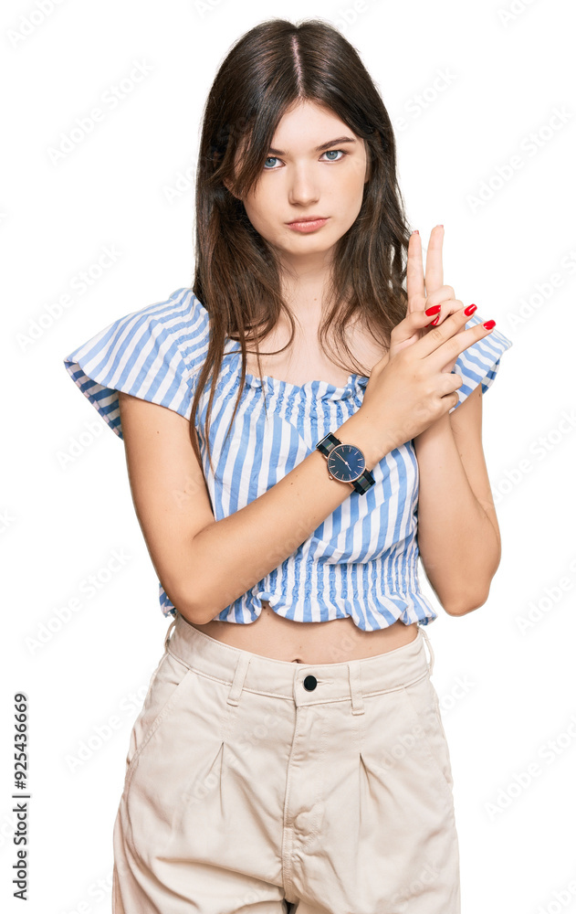 Young beautiful caucasian girl wearing casual clothes holding symbolic gun with hand gesture, playing killing shooting weapons, angry face