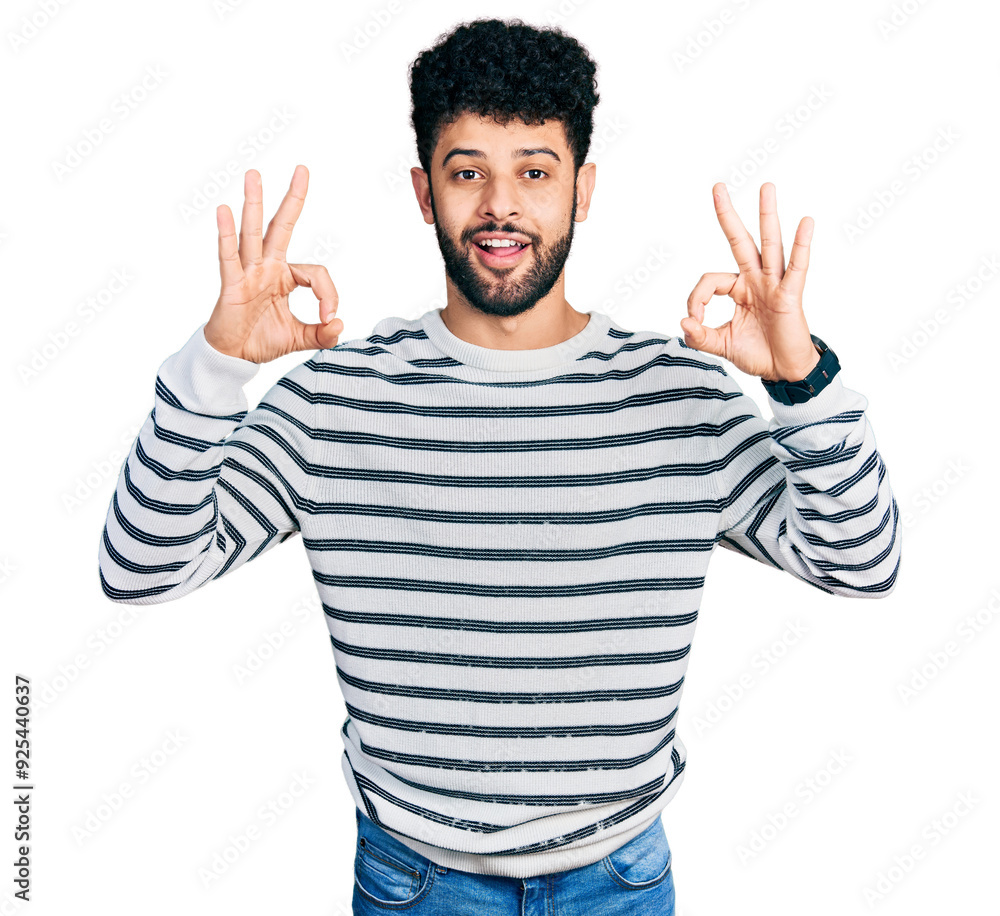 Naklejka premium Young arab man with beard wearing casual striped sweater looking surprised and shocked doing ok approval symbol with fingers. crazy expression