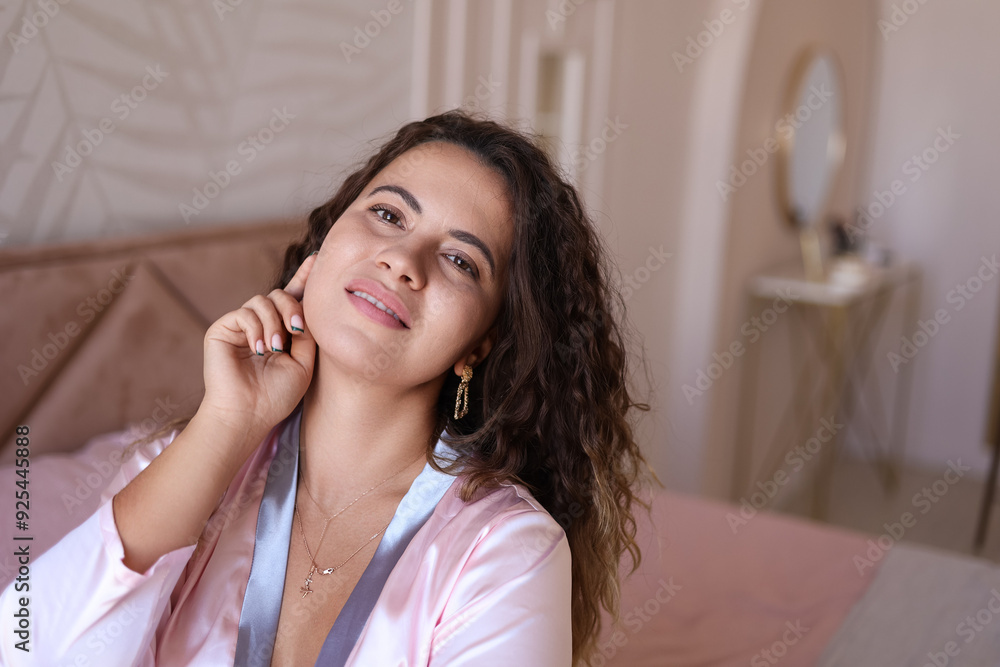 A beautiful curly-haired girl in a pink silk pajamas lies on the bed, relaxed. A middle-aged woman is getting ready for bed in the morning, smiling. Girl has fun on her bed at home, jumping A beautiful curly-haired girl in a pink silk pajamas lies on the bed, relaxed. A middle-aged woman is getting ready for bed in the morning, smiling. Girl has fun on her bed at home, jumping