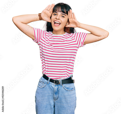 Young hispanic girl wearing casual clothes smiling cheerful playing peek a boo with hands showing face. surprised and exited photo