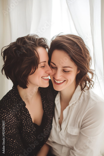 A beautiful gay couple shares a tender kiss and laughter, their joy illuminated against a backdrop of white curtains.