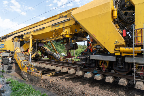 Bild auf Leinwand Baumaschine ersetzt den Schotter am Gleis