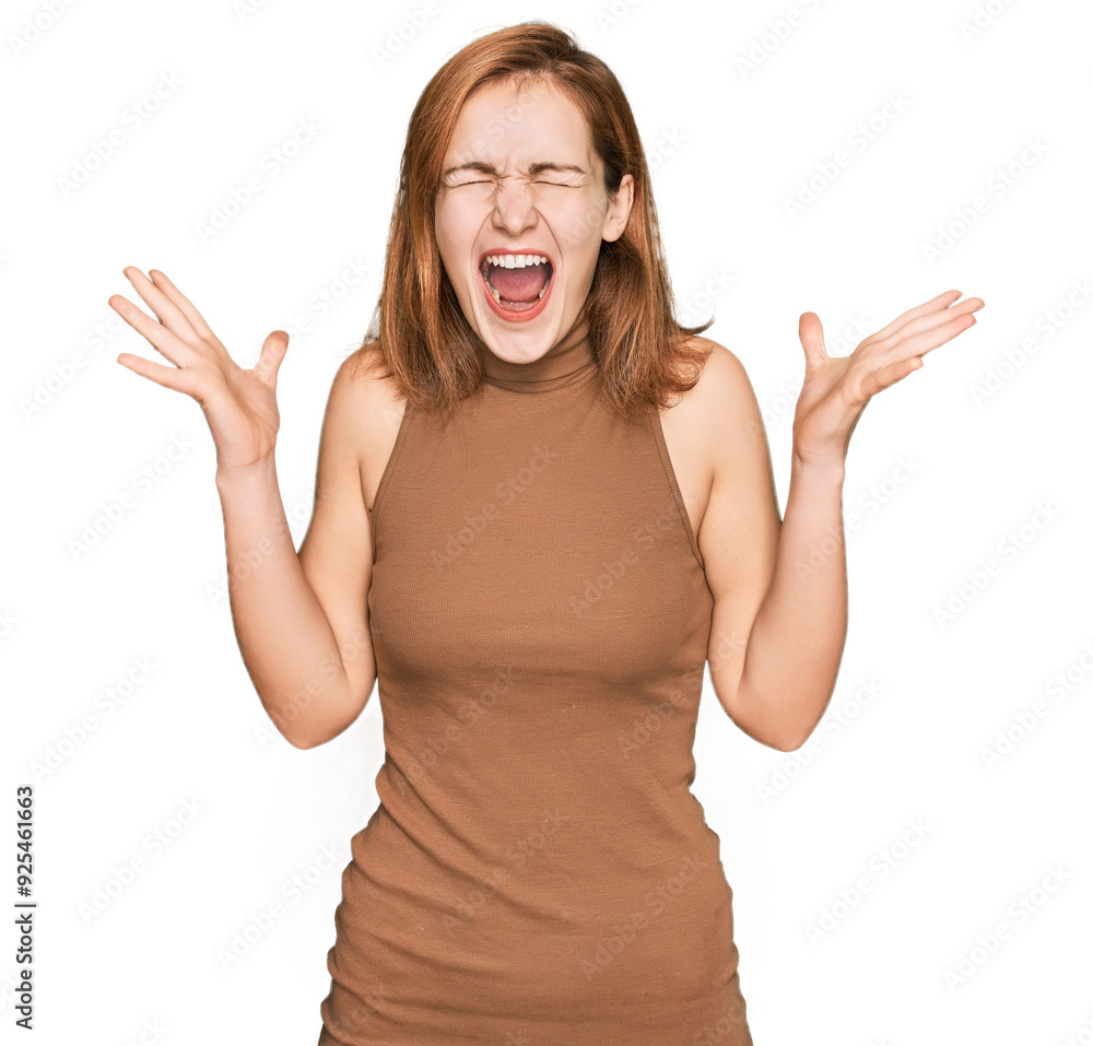 Young caucasian woman wearing casual clothes celebrating mad and crazy for success with arms raised and closed eyes screaming excited. winner concept