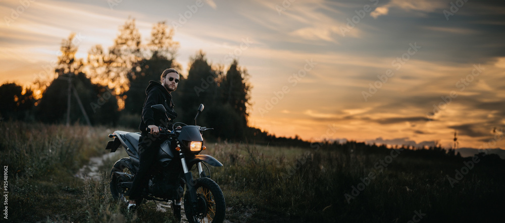 brutal male motorcyclist in sunglasses on a motard motorcycle outside the city