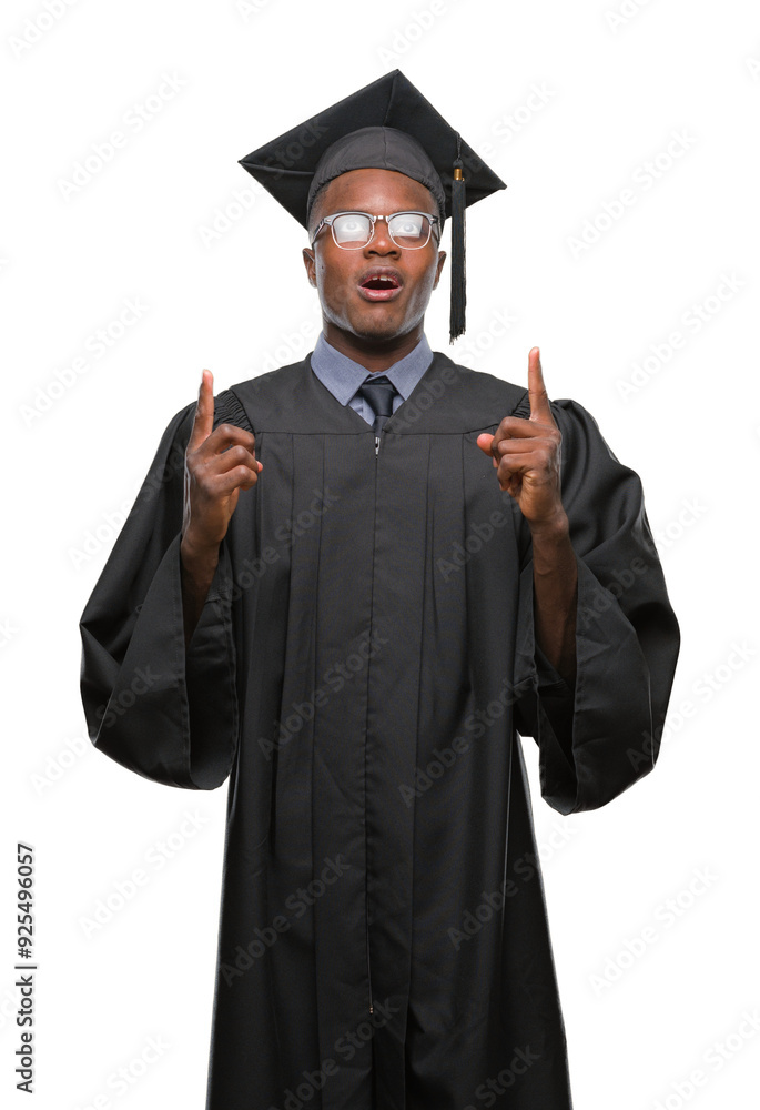 Young graduated african american man over isolated background amazed and surprised looking up and pointing with fingers and raised arms. Young graduated african american man over isolated background amazed and surprised looking up and pointing with fingers and raised arms.