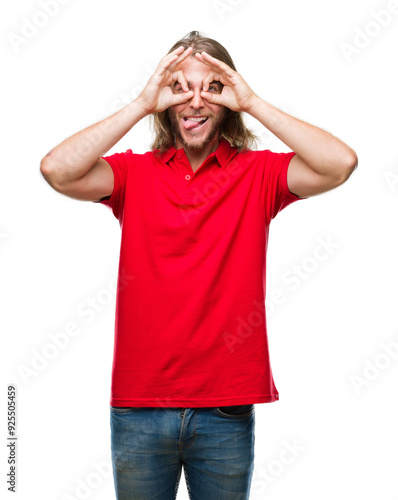 Young handsome man with long hair over isolated background doing ok gesture like binoculars sticking tongue out, eyes looking through fingers. Crazy expression.