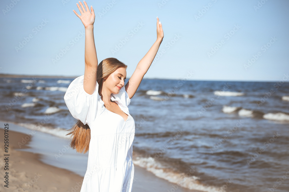 Happy smiling beautiful woman on the ocean beach standing in a white summer dress, raising hands Happy smiling beautiful woman on the ocean beach standing in a white summer dress, raising hands