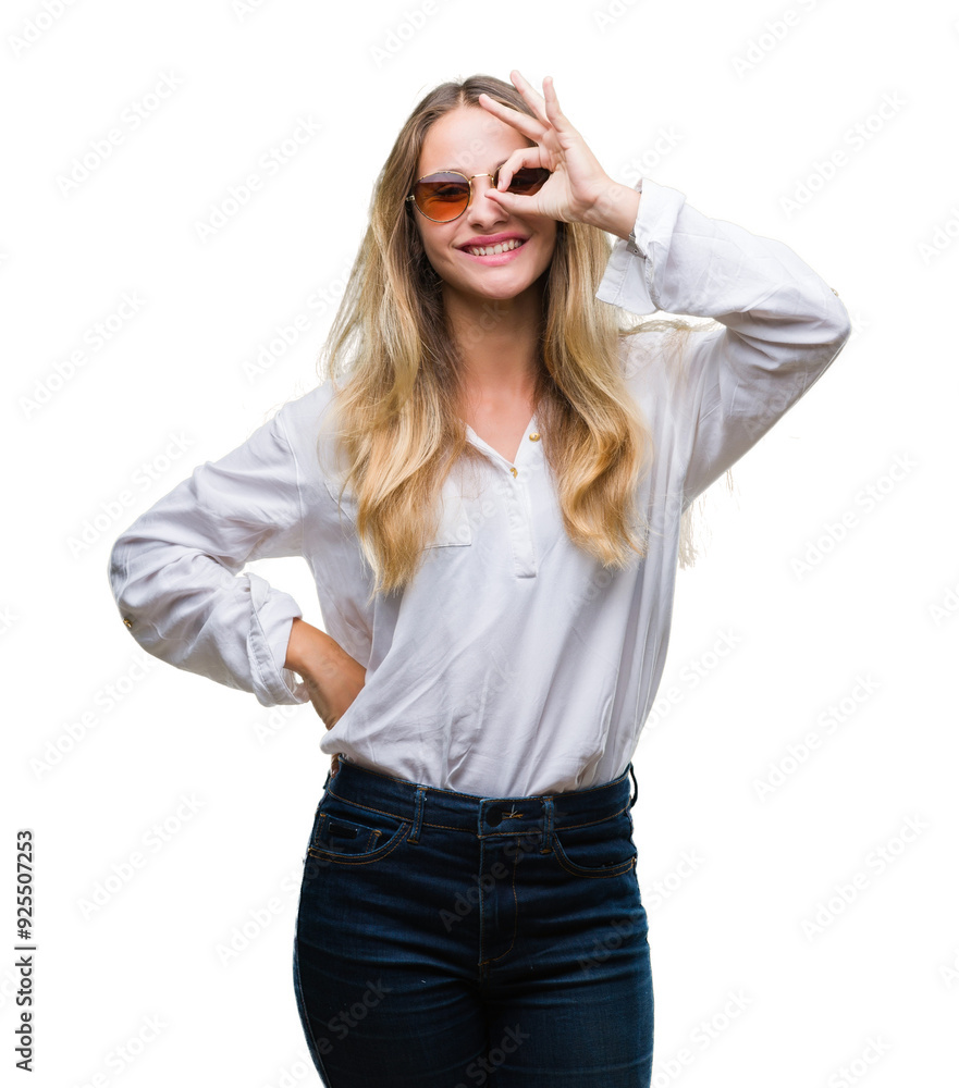 Young beautiful blonde woman wearing sunglasses over isolated background doing ok gesture with hand smiling, eye looking through fingers with happy face. Young beautiful blonde woman wearing sunglasses over isolated background doing ok gesture with hand smiling, eye looking through fingers with happy face.