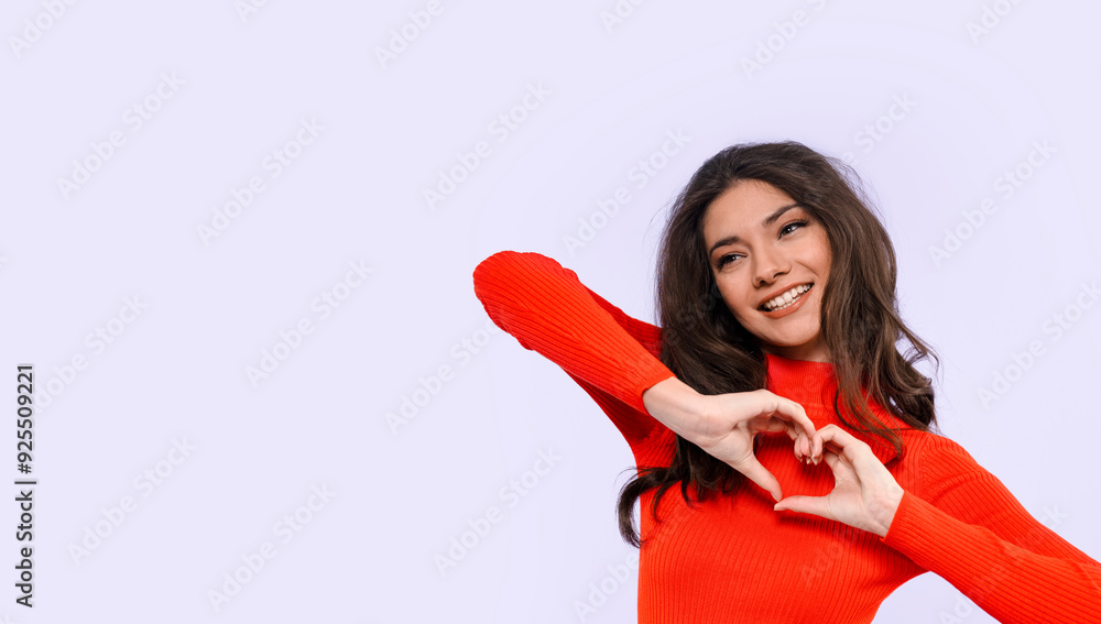Young Woman in Red Sweater Making Heart Shape With Her Hands, Smiling Against Light Background Young Woman in Red Sweater Making Heart Shape With Her Hands, Smiling Against Light Background