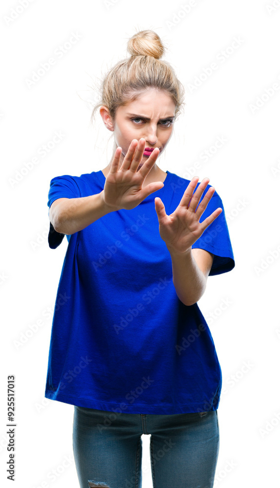 Young beautiful blonde and blue eyes woman wearing blue t-shirt over isolated background afraid and terrified with fear expression stop gesture with hands, shouting in shock. Panic concept. Young beautiful blonde and blue eyes woman wearing blue t-shirt over isolated background afraid and terrified with fear expression stop gesture with hands, shouting in shock. Panic concept.
