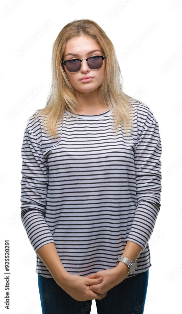 Young caucasian woman wearing sunglasses over isolated background with serious expression on face. Simple and natural looking at the camera. Young caucasian woman wearing sunglasses over isolated background with serious expression on face. Simple and natural looking at the camera.