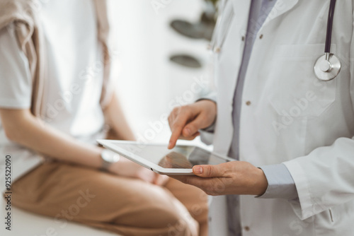 Doctor and patient in clinic. Friendly physician using tablet computer near a young woman. Medicine concept