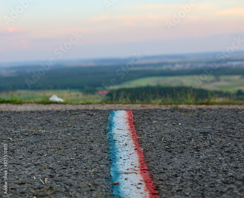 Ein blau-weiß-roter Streifen wie die französische Flagge auf der Straße, mit einer schönen Landschaft als weichem Hintergrund.