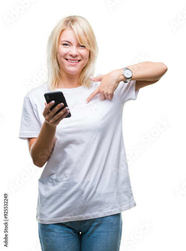 Young beautiful blonde woman using smartphone over isolated background with surprise face pointing finger to himself