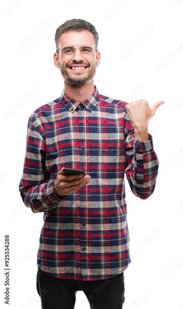 Young hipster adult man holding smartphone pointing and showing with thumb up to the side with happy face smiling Young hipster adult man holding smartphone pointing and showing with thumb up to the side with happy face smiling