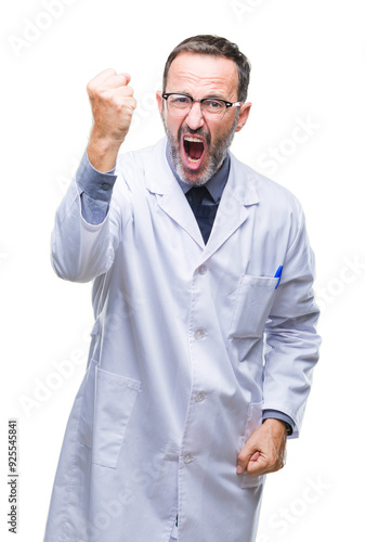 Middle age senior hoary professional man wearing white coat over isolated background angry and mad raising fist frustrated and furious while shouting with anger. Rage and aggressive concept.