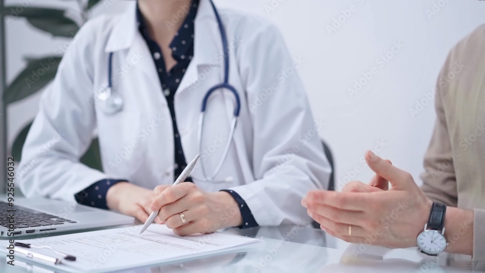 Doctor and patient are talking in clinic after health check up. Female physician is making notes. Medicine concept Doctor and patient are talking in clinic after health check up. Female physician is making notes. Medicine concept