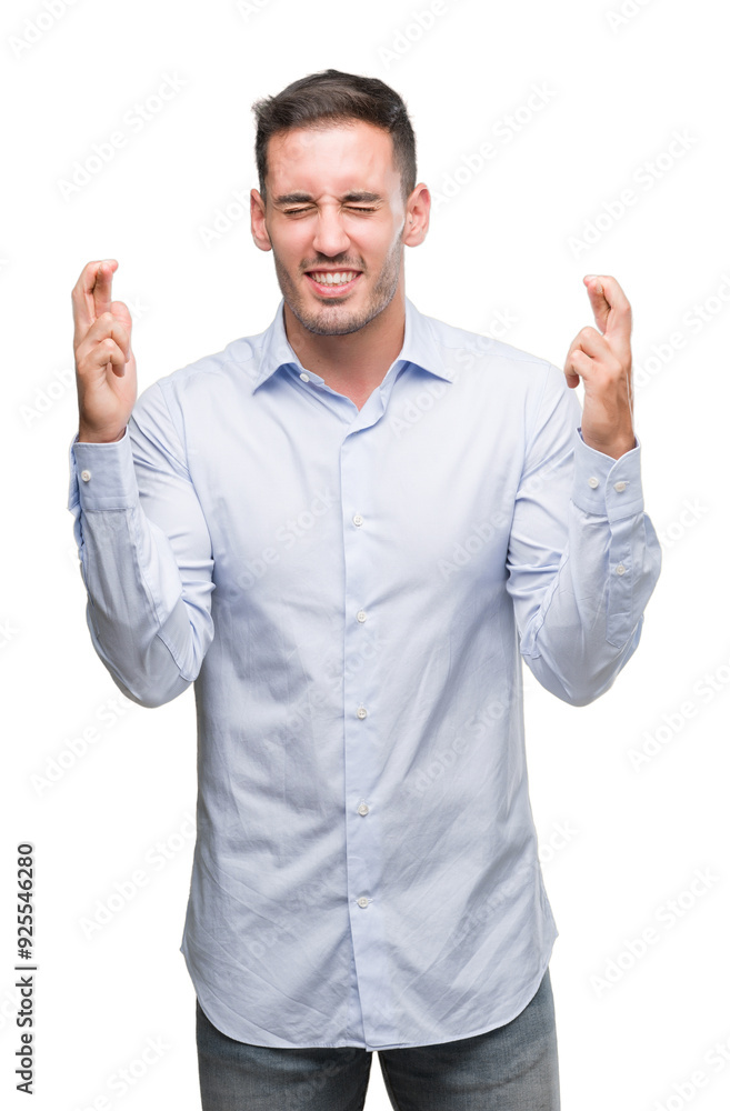 Handsome young businessman smiling crossing fingers with hope and eyes closed. Luck and superstitious concept. Handsome young businessman smiling crossing fingers with hope and eyes closed. Luck and superstitious concept.