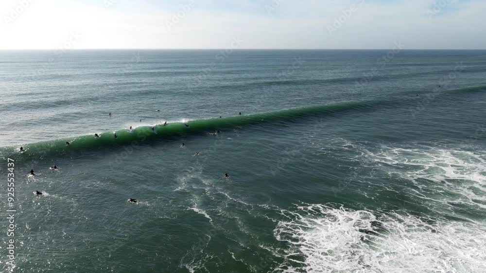 Aerial view of surfers in the Pacific Ocean at Swamis Beach catching waves on partly cloudy day at crowded famous surf spot Aerial view of surfers in the Pacific Ocean at Swamis Beach catching waves on partly cloudy day at crowded famous surf spot