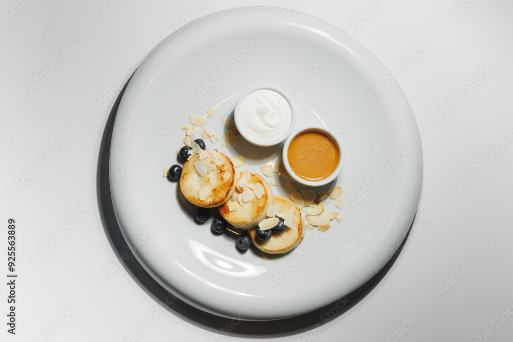 Appetizing cheese pancakes with blueberries and honey on a large white plate Appetizing cheese pancakes with blueberries and honey on a large white plate