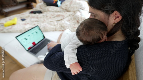 Mother working on a laptop while holding a newborn baby, showcasing balance of professional duties and parental responsibilities, emphasizing modern family life and multitasking skills