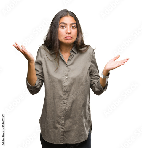 Young beautiful arab woman over isolated background clueless and confused expression with arms and hands raised. Doubt concept. photo