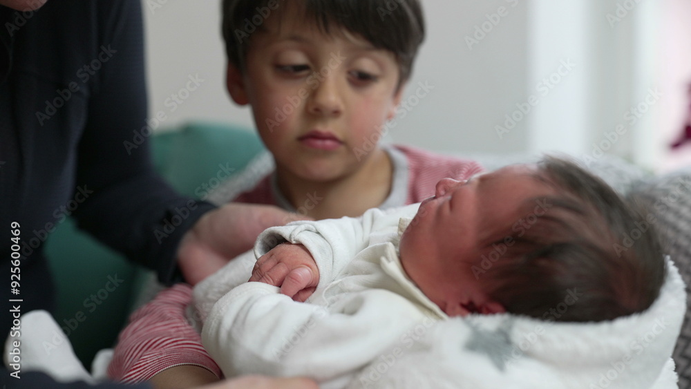 Young boy gently holding newborn sibling, with mother close by, exploring family dynamics, nurturing, and sibling bond, cozy indoor scene, emotional connection Young boy gently holding newborn sibling, with mother close by, exploring family dynamics, nurturing, and sibling bond, cozy indoor scene, emotional connection