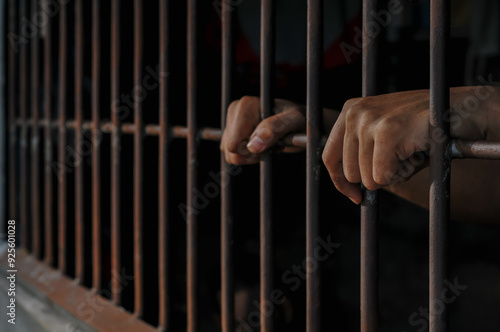 prisoner's hands behind bars
