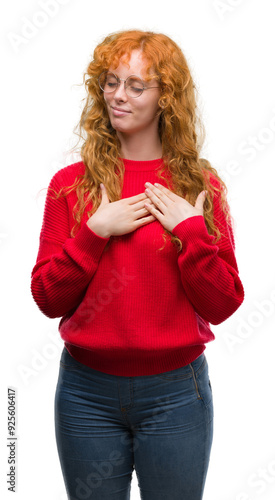 Young redhead woman wearing red sweater smiling with hands on chest with closed eyes and grateful gesture on face. Health concept.