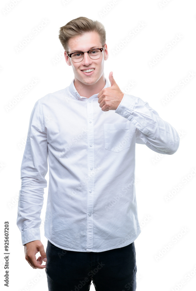 Young handsome blond man doing happy thumbs up gesture with hand. Approving expression looking at the camera with showing success. Young handsome blond man doing happy thumbs up gesture with hand. Approving expression looking at the camera with showing success.