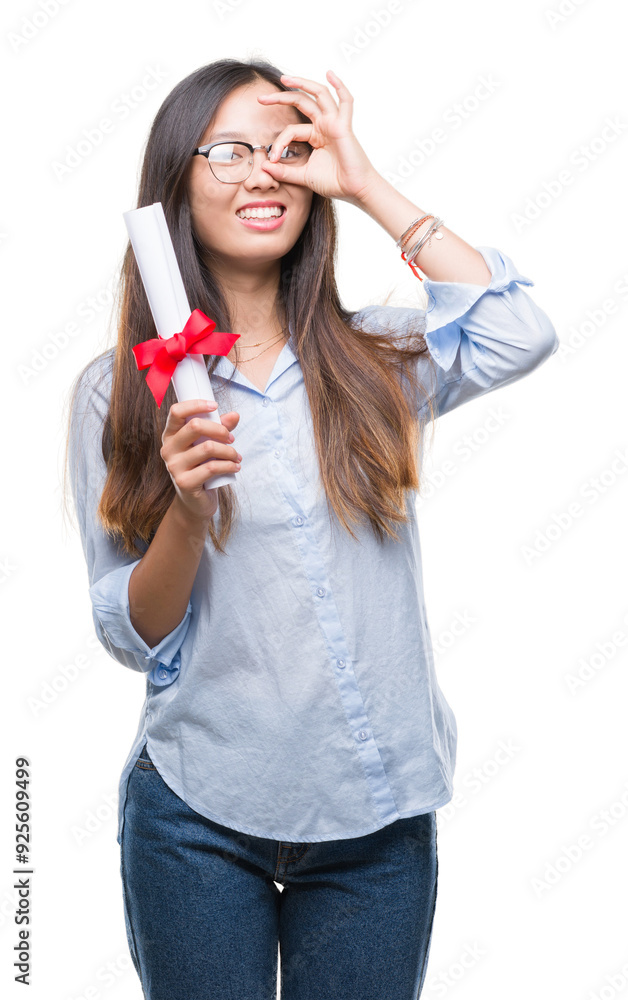Young asian woman holding degree over isolated background with happy face smiling doing ok sign with hand on eye looking through fingers Young asian woman holding degree over isolated background with happy face smiling doing ok sign with hand on eye looking through fingers