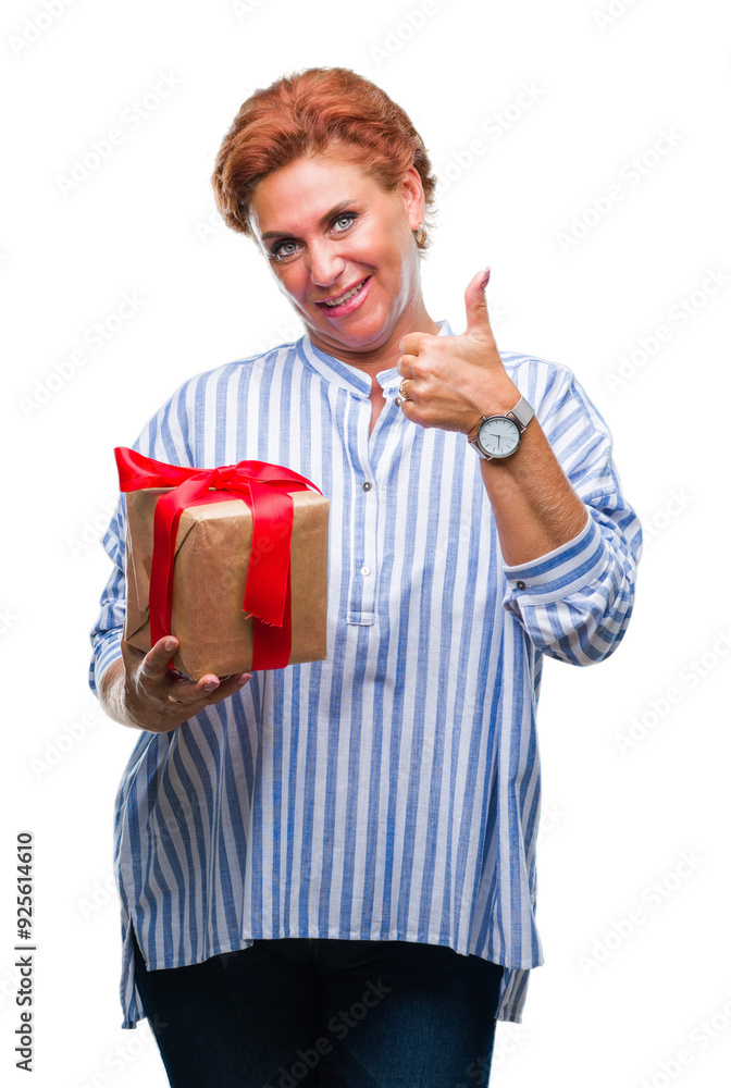 Senior caucasian woman holding gift over isolated background happy with big smile doing ok sign, thumb up with fingers, excellent sign Senior caucasian woman holding gift over isolated background happy with big smile doing ok sign, thumb up with fingers, excellent sign