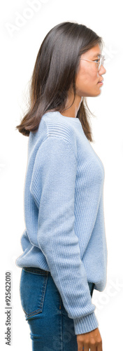 Young asian woman wearing winter sweater over isolated background looking to side, relax profile pose with natural face with confident smile.