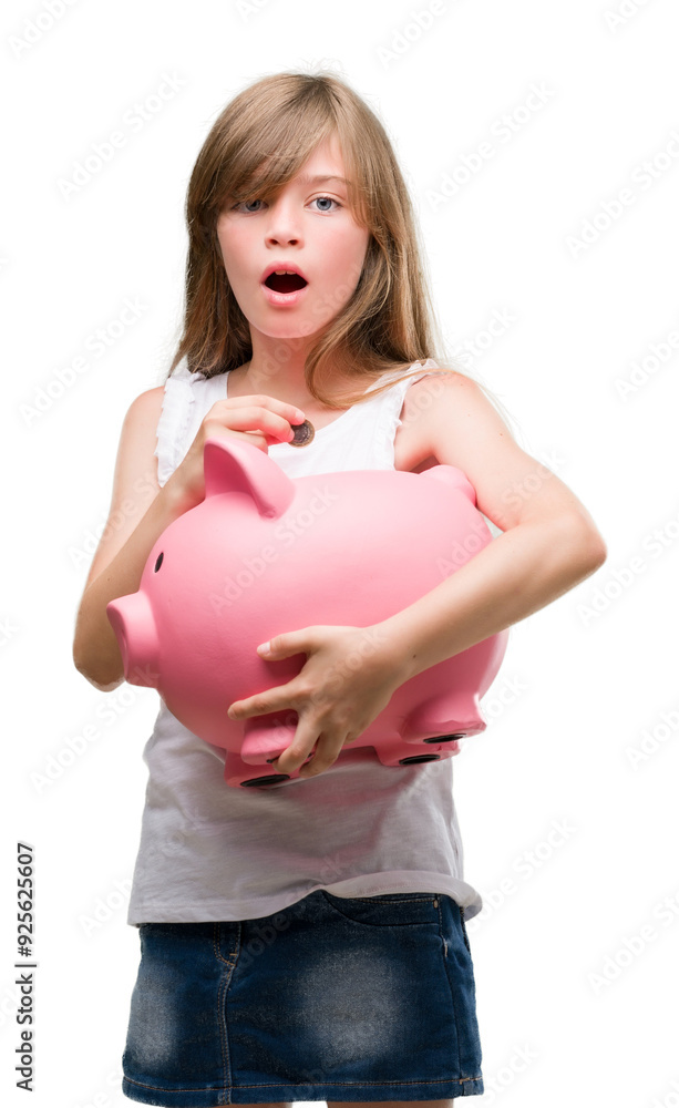 Young blonde toddler holding piggy bank scared in shock with a surprise face, afraid and excited with fear expression Young blonde toddler holding piggy bank scared in shock with a surprise face, afraid and excited with fear expression