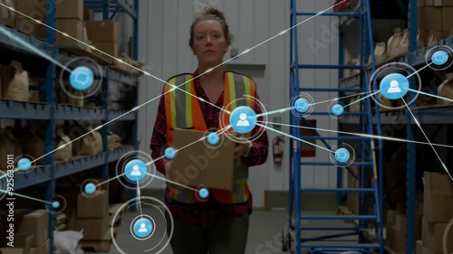 Warehouse worker carrying box with network connections animation over shelves photo