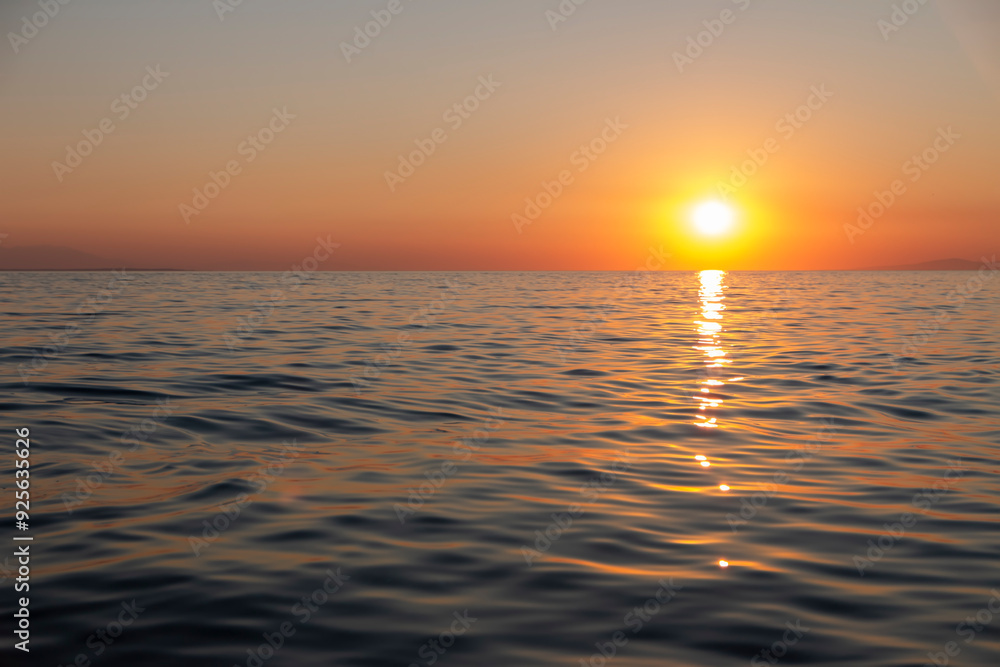 Fototapeta premium The gorgeous golden sun descends towards the horizon, casting a warm and mesmerizing glow over the tranquil waves of the ocean, creating a breathtaking and serene scene.