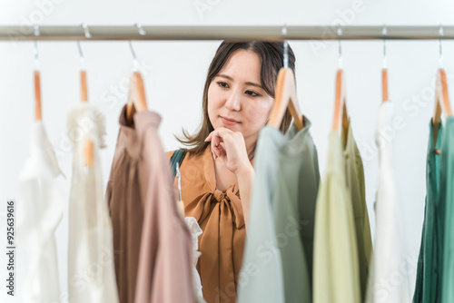 фотографія 家・洋服屋・アパレルショップで洋服を選ぶ女性（ファッション・ショッピング）