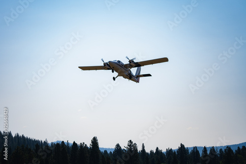 Twin Otter airplane takes off over pine trees