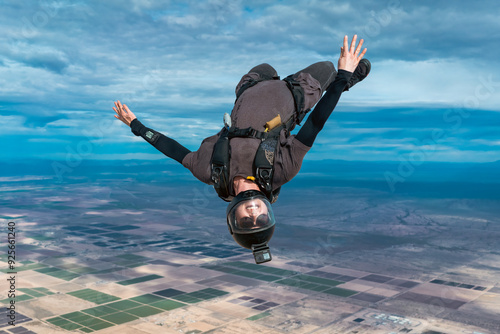 Upside down woman makes skydive alone over desert with dramatic cloudy landscape