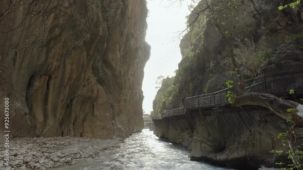 A serene scene of a narrow canyon with a flowing river and a wooden walkway along the cliffside, offering a peaceful retreat in nature. A serene scene of a narrow canyon with a flowing river and a wooden walkway along the cliffside, offering a peaceful retreat in nature.
