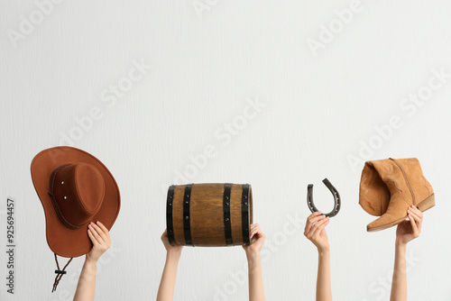 Female hands with cowboy hat, shoe, barrel and horseshoe on light background