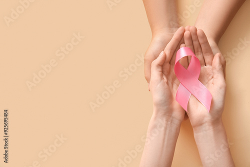 Female hands with pink awareness ribbon on color background, closeup. Breast cancer concept