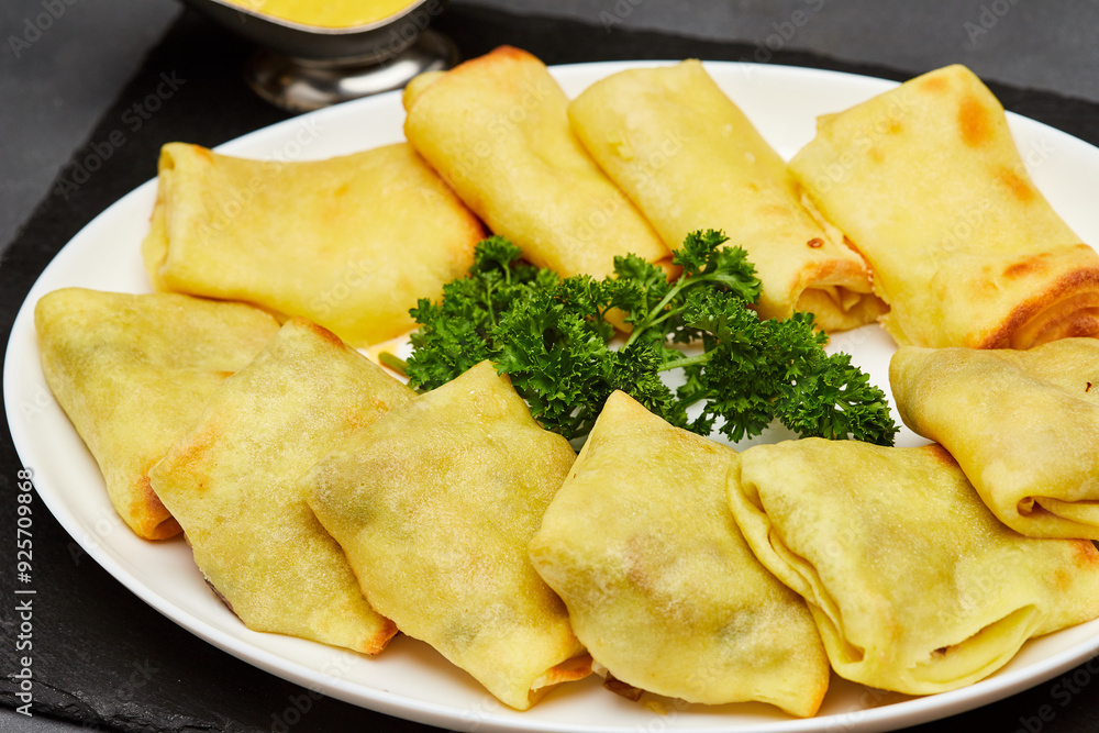 Golden baked crepes stuffed with savory filling, served with fresh parsley garnish on a white plate Golden baked crepes stuffed with savory filling, served with fresh parsley garnish on a white plate
