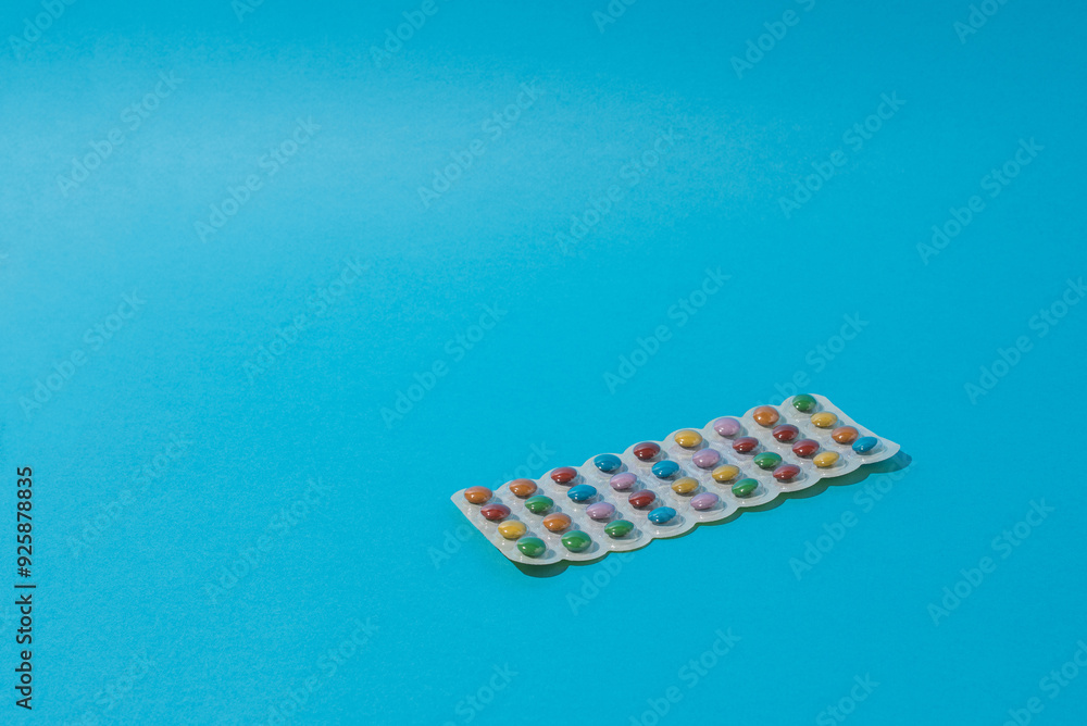 Colorful candies packed in medicine foil on blue background. Minimum art. Colorful candies packed in medicine foil on blue background. Minimum art.