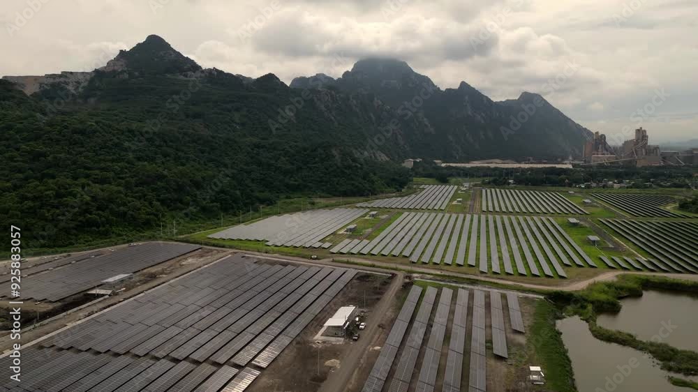 A large field of solar panels is shown in the image. The panels are arranged in rows and are spread across the landscape. The sun is shining brightly, illuminating the area A large field of solar panels is shown in the image. The panels are arranged in rows and are spread across the landscape. The sun is shining brightly, illuminating the area