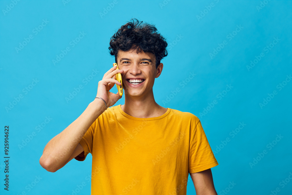 cheerful young man talking on the phone, blue background, vibrant colors, smiling face, engaging phone conversation, happiness, youthfulness, lifestyle concept, modern communication cheerful young man talking on the phone, blue background, vibrant colors, smiling face, engaging phone conversation, happiness, youthfulness, lifestyle concept, modern communication