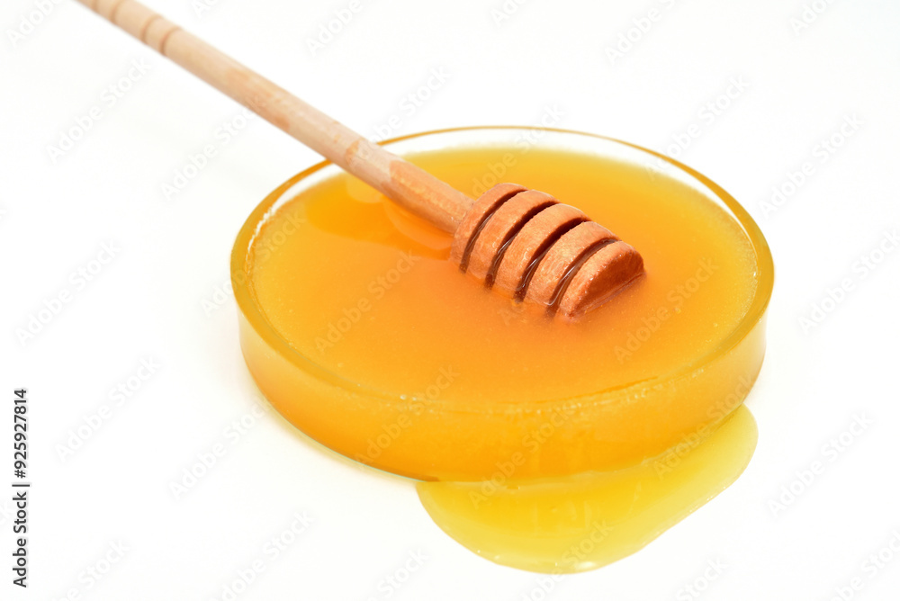 Honey with wooden honey dipper in the glass bowl isolated on the white background. Close-up. Copy space. Selective focus. Honey with wooden honey dipper in the glass bowl isolated on the white background. Close-up. Copy space. Selective focus.