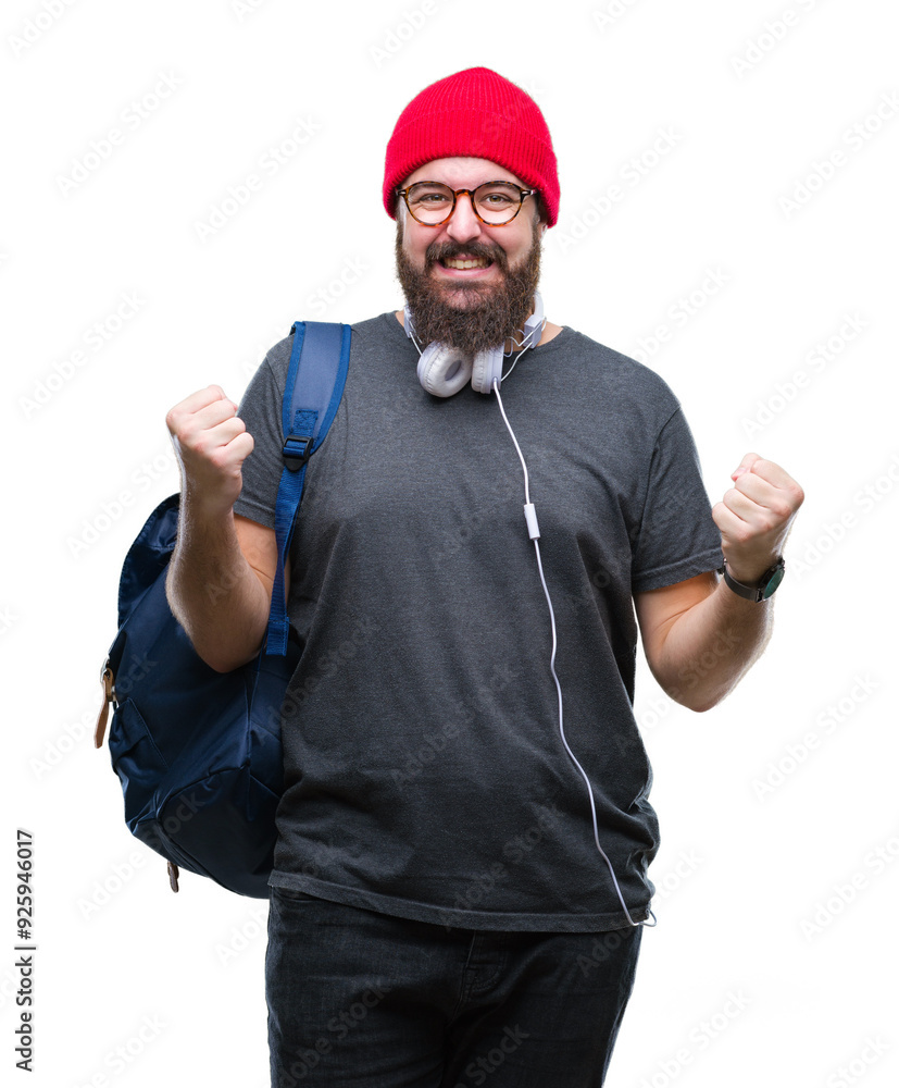 Fototapeta premium Young hipster man wearing red wool cap and backpack over isolated background celebrating surprised and amazed for success with arms raised and open eyes. Winner concept.