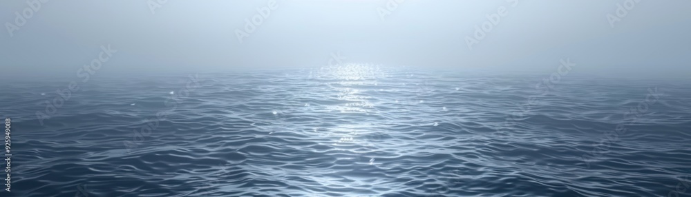 Naklejka premium Calm ocean with misty horizon, blue water waves reflecting sunlight under cloudy sky, tranquil and serene seascape.