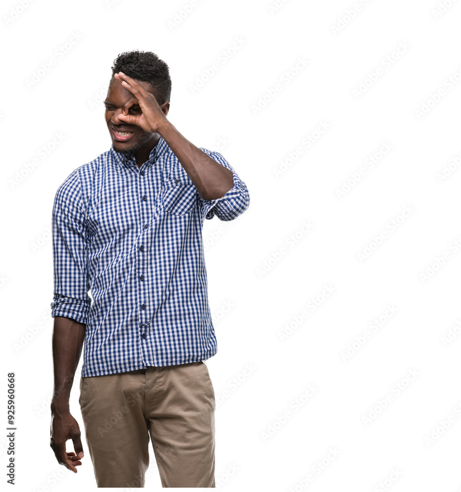 Young african american man wearing blue shirt doing ok gesture with hand smiling, eye looking through fingers with happy face. Young african american man wearing blue shirt doing ok gesture with hand smiling, eye looking through fingers with happy face.